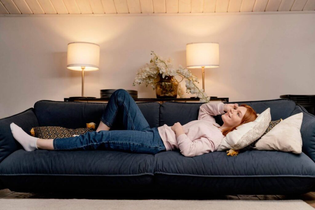 Mulher deitada em sofa cama aberto em sala pequena – conforto e praticidade para espaços compactos